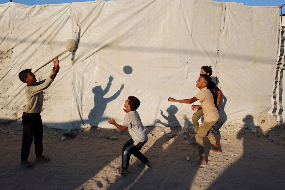 Niños palestinos desplazados juegan con una pelota frente a una tienda de campaña en la ciudad de Gaza el 31 de agosto de 2026. En octubre se alcanzó un alto el fuego en Gaza entre Israel y Hamás tras dos años de guerra, conflicto desencadenado por el ataque sin precedentes de los milicianos palestinos contra Israel el 7 de octubre de 2023. La segunda fase del alto el fuego, que debía incluir el desarme de Hamás y la retirada gradual de las fuerzas israelíes de Gaza, lleva meses estancada. (Foto de Omar AL-QATTAA / AFP)