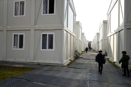 Niños que regresan de la escuela caminan entre apartamentos construidos con contenedores en un vecindario para familias ucranianas huidas de la guerra en Linkeroever, Bélgica, el viernes 17 de marzo de 2023.