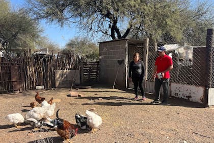 Noel en su casa junto a su mamá Alicia dándole de comer a las gallinas
