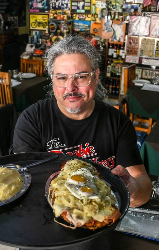 Norberto Meza con la milanesa Don Ignacio, que lleva salsa, mozzarella, jamón, cebolla, orégano y dos huevos fritos