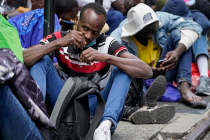 Numerosos migrantes permanecen día y noche en una acera afuera del hotel Roosevelt alquilado por la ciudad como lugar de alojamiento temporal (AP Foto/John Minchillo)