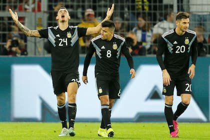 Ocampos celebra su primer gol en su bautismo en la selección; lo acompañan Acuña y Alario