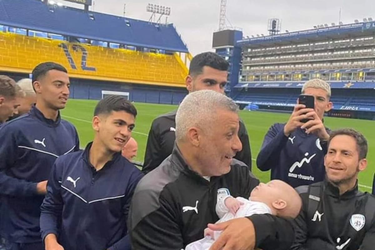 Ofer Haim, entrenador de la selección israelí Sub 20, con un bebé en brazos y algunos de sus jugadores durante una visita a la Bombonera