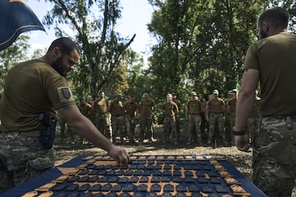 Oficiales de la 3ª Brigada de Asalto Separada de Ucrania entregan a los soldados los emblemas de la brigada cerca de Bakhmut, el lugar de feroces batallas con las fuerzas rusas en la región de Donetsk, Ucrania, el domingo 3 de septiembre de 2023. (AP Photo/Libkos)