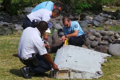 Oficiales de policía inspeccionan un resto del avión encontrado en la isla de La Reunión, en el Océano Índico