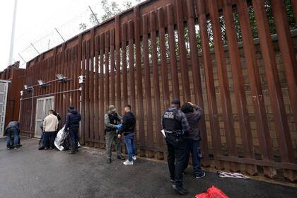 Oficiales federales estadounidenses le quitan las esposas a hombres antes de liberarlos cerca de la muralla fronteriza en San Diego el 15 de marzo de 2023. (Foto AP /Gregory Bull)