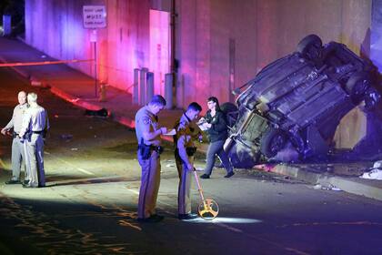 Oficiales trabajan en el lugar donde ocurrió un accidente vehicular en Pasadena, California, el 16 de enero de 2022. Tres personas murieron al caer el automóvil en el que viajaban desde una sección elevada de la autopista. (AP Foto/James Carbone)