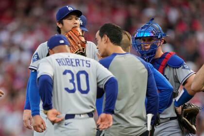 Ohtani deja el montículo acompañado por un entrenador tras lanzar seis bolas