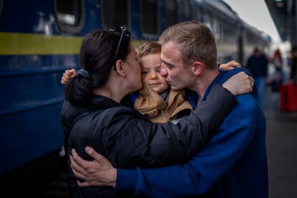 Oleksandr de 26 años, besa a su hijo Egor de 2 años  y a su esposa Alyona de 26, al reunirse en la estación de tren después de más de dos meses separados por la guerra en Kiev, Ucrania, el sábado 23 de abril de 2022