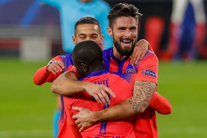 Olivier Giroud se abraza con su compañero N´Golo Kanté luego de convertir uno de los cuatro goles de Chelsea en el partido ante Sevilla por la Champions League. Detrás suyo se suma el marroquí Hakim Ziyech.