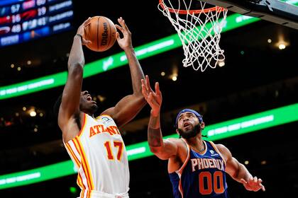Onyeka Okongwu (17), de los Hawks de Atlanta, captura un rebote cerca de JaVale McGee (00), de los Suns de Phoenix, en la primera mitad del partido de la NBA en Atlanta, el jueves 3 de febrero de 2022. (AP Foto/John Bazemore)