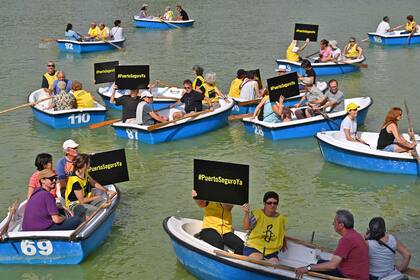 Activistas viajan en botes y con carteles en el Parque del Retiro de Madrid durante una campaña de sensibilización organizada por Amnistía Internacional