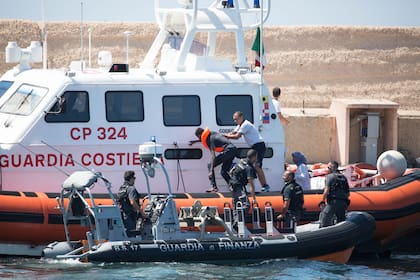 Guardias costeros transportan a un inmigrante al puerto de Lampedusa desde el barco "Open Arms" de la ONG que lleva el mismo nombre