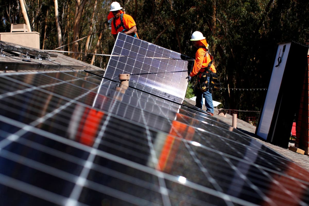 Operarios instalan paneles de energía solar en el techo de una casa en California