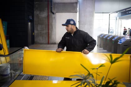 Operarios trabajan sobre el sector inferior de la escalera mecánica, que continúa fuera de servicio