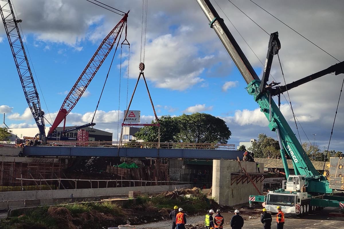 Operarios y grúas de gran porte durante el montaje de una de las vigas del nuevo puente sobre la calle Río Negro, en plena traza de la autopista Dellepiane