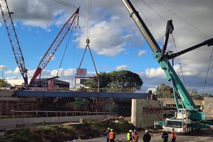 Operarios y grúas de gran porte durante el montaje de una de las vigas del nuevo puente sobre la calle Río Negro, en plena traza de la autopista Dellepiane