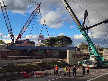 Operarios y grúas de gran porte durante el montaje de una de las vigas del nuevo puente sobre la calle Río Negro, en plena traza de la autopista Dellepiane