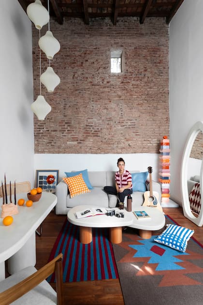 Ornella D'Elia en su colorido living. Alfombras de lana (Seara). Lámparas colgantes (Juan Diciervo). De microcemento, mesas bajas con patas de haya hechas a mano por Achalilas.