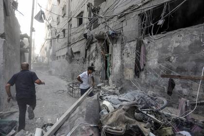 os palestinos inspeccionan los escombros de un edificio destruido tras un ataque israelí