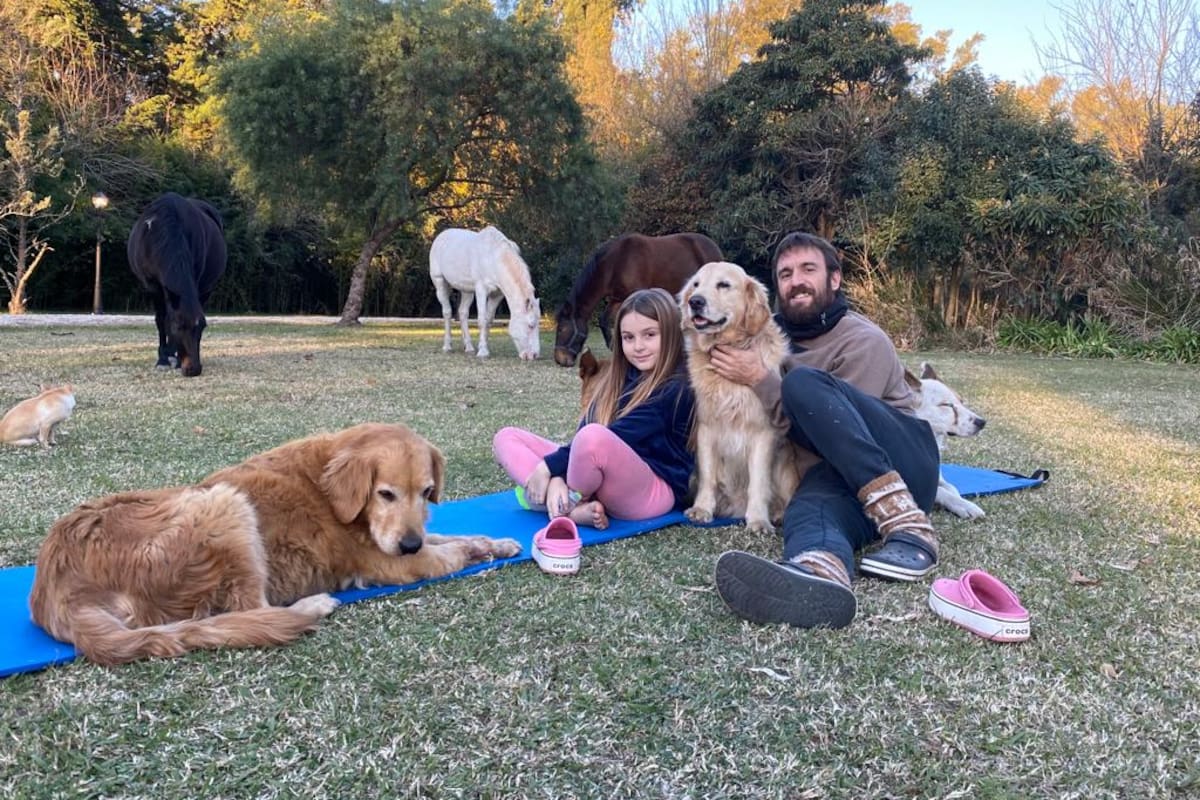 Oscar Ahumada, en su remanso, junto a una de sus hijas, Sofía, sus mascotas y los caballos en su campo en las afueras de Zárate