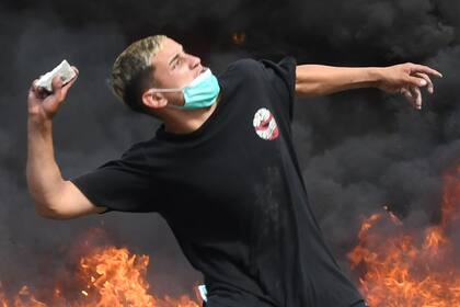 Otro de los agresores, entre las llamas y el humo negro por la quema de neumáticos y contenedores de basura