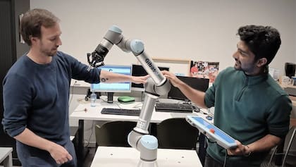 Pablo Lanillos, coordinador del proyecto Metatool, (a la izquierda) y el investigador postdoctoral Ajith Anil Meera trabajan con uno de sus robots industriales