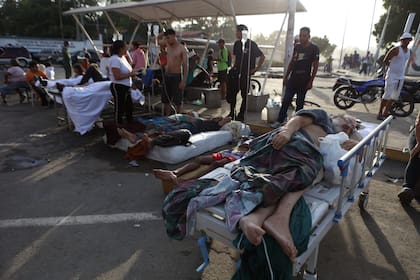 Pacientes permanecen recostados afuera de un hospital evacuado tras resultar dañado por un terremoto en Catia La Mar