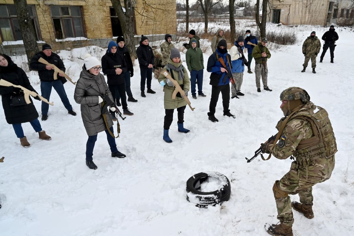 Pag 3 Un instructor militar enseña a civiles que sostienen réplicas de madera de rifles Kalashnikov, durante una sesión de entrenamiento en una fábrica abandonada en la capital ucraniana de Kiev el 30 de enero de 2022. - A medida que crecen los temores de una posible invasión de tropas rusas concentradas en la frontera de Ucrania, en el marco del entrenamiento hubo clases de táctica, paramédicos, entrenamiento en la carrera de obstáculos. El entrenamiento está a cargo de instructores con experiencia en combate, miembros de la iniciativa pública "Resistencia Total". (Foto de Serguéi SUPINSKY / AFP)