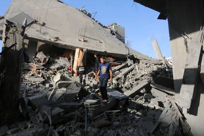 Palestinos caminan entre los restos de edificios destruidos en bombardeos israelíes sobre la Franja de Gaza, en Rafah, el 7 de noviembre de 2023.