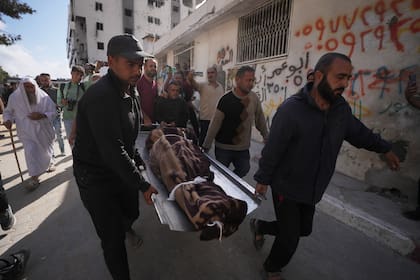 Palestinos cargan con el cuerpo de una persona fallecida en la víspera en ataques aéreos israelíes contra Izz al-Din al-Haddad, líder de las Brigadas Qassam de Hamás
