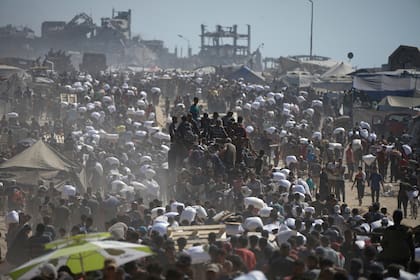 Palestinos cargan sacos de harina sacados de un convoy de ayuda humanitaria que se dirigía a la Ciudad de Gaza (AP Foto/Jehad Alshrafi)