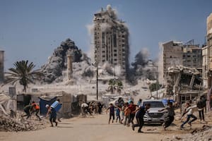 Palestinos corren a cubrirse durante un ataque israelí contra un edificio alto en Ciudad de Gaza (AP Foto/Yousef Al Zanoun, Archivo)