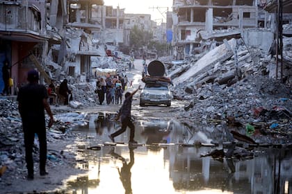Palestinos desplazados por la ofensiva terrestre y aérea de Israel en la Franja de Gaza caminan cerca de aguas residuales en las calles del poblado de Jan Yuni.