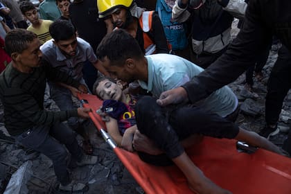 Palestinos evacuan a los heridos tras un bombardeo que destruyó un edificio en Khan Younis, en la Franja de Gaza. (AP Foto/Fatima Shbair)