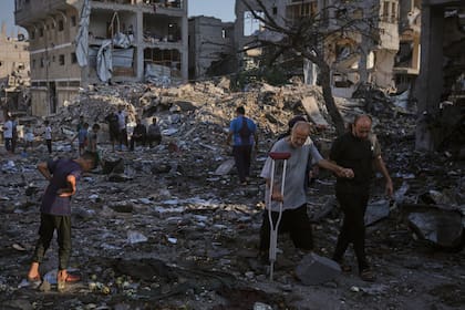 Palestinos inspeccionan los escombros de edificios y tiendas de campañas destruidas por un ataque israelí en Ciudad de Gaza
