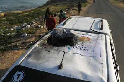 Palestinos inspeccionan un vehículo con el logotipo de World Central Kitchen alcanzado por un ataque aéreo israelí en Deir al Balah, Franja de Gaza, el martes 2 de abril de 2024. (AP Foto/Ismael Abu Dayyah)