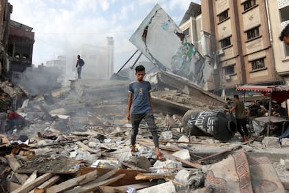 Palestinos inspeccionando daños a edificios y casas en Khan Younis luego de los ataques aéreos israelíes, en el sur de la Franja de Gaza, el 10 de octubre de 2023 (Yousef Masoud/The New York Times)