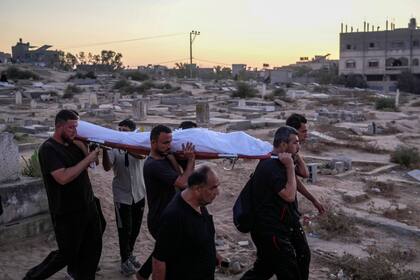 Palestinos llevan a un muerto para ser sepultado en el cementerio en Deir al-Balah, Franja de Gaza, el 9 de agosto del 2024. (Foto AP/Abdel Kareem Hana)