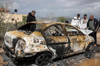 Palestinos observan uno de los coches quemados por colonos israelíes en Fandaqumiya, cerca de Jenin