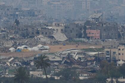 Palestinos se ven cerca de edificios destruidos por bombardeos israelíes dentro de la Franja de Gaza, visto desde el sur de Israel, el domingo 9 de febrero de 2025