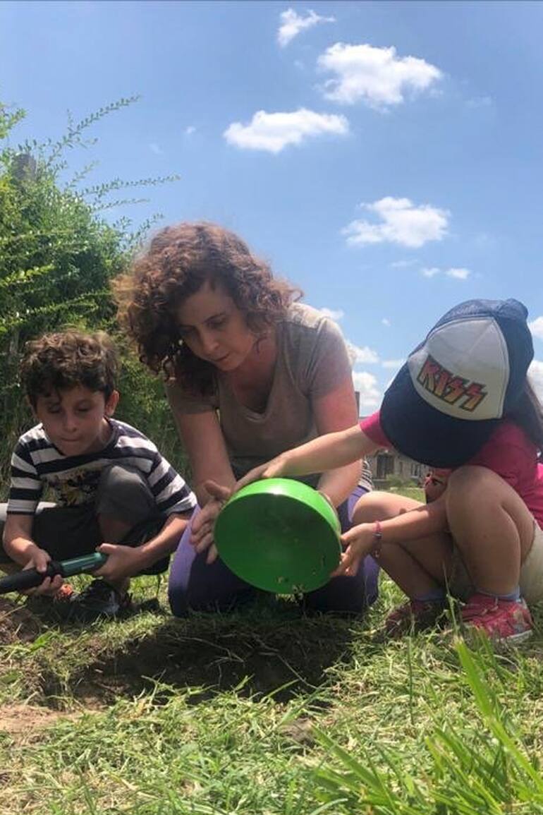 Mariel Klosewicz junto a sus hijos Lorenzo y Renata haciendo tareas de huerta en el jadín de su casa
