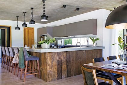 Tanto el momento de cocinar como el de comer se vuelven un espectáculo compartido en la barra con base de yeso revestido en lapacho y tapa de hormigón. Banquetas tapizadas en lino spring stonewashed (Estudio Pirca).