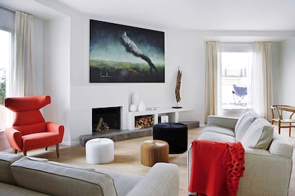 Para conformar el living, dos sillones de tres cuerpos se ubicaron formando un triángulo con el flamante hogar de líneas minimalistas y con leñero de obra. Sofá danés rojo original de los 50.