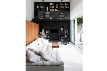 Para cortar el efecto pasillo de este living, se sumó el mueble en negro y la biblioteca superior en el mismo tono. El pequeño toque de madera aporta calidez al conjunto