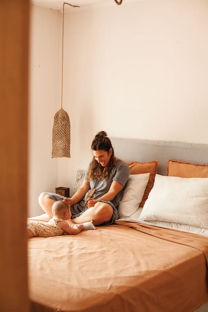 Para el dormitorio principal, Nadia eligió todo reversible porque se aburre rápido. Eligió una combinación verde seco y terracota que es más “campo” y después sumó rayas en gris y blanco para verano, porque es más playero. La lámpara hecha a mano es de Vero Alessandrini.