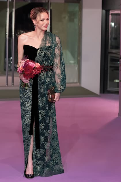 Para esta ocasión, Charlene eligió un original diseño en encaje verde que fusionaba la fluidez de una túnica con la sobria estructura de un vestido midi negro y que, al igual que su clutch dorado, era de Dolce & Gabbana.