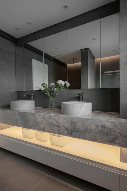 Para jugar con las texturas, se eligió una piedra natural para los revestimientos del baño y mármol de Carrara claro para la mesada.