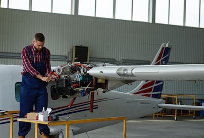 Young man repairing airplane in hangar