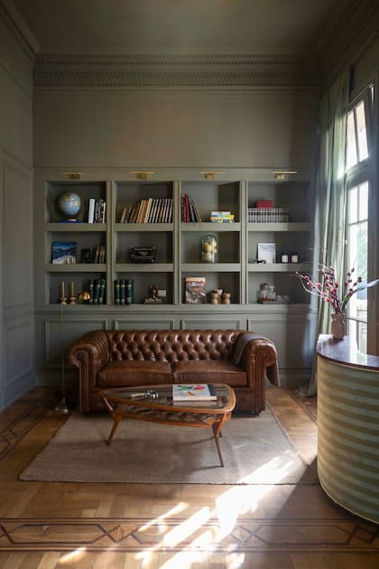 Para una atmósfera profunda, pintaron todo en ‘Connected Gray’ (Sherwin Williams). Alfombra de lana ‘Monte’ (Elementos Argentinos), mesa ratona años 60 (Englander & Bonta) y sillón ‘Chesterfield’ de cuero.